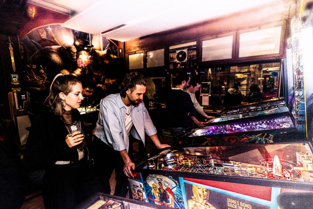 Bezoekers spelen pinball in Café Comic Sans Brussel